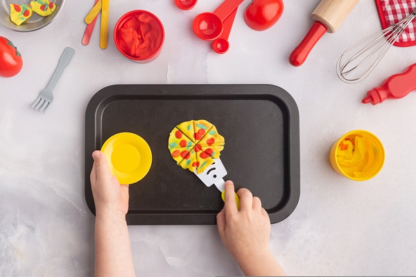 copil care lucreaza cu plastilina pentru a-si crea propria mini-pizza