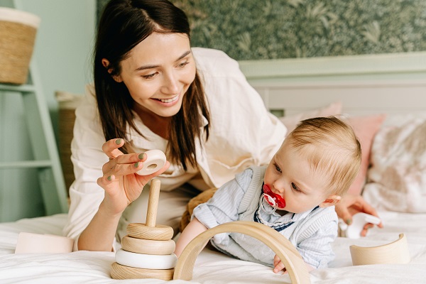 mama care se joaca cu bebelusul ei cu jucarii de lemn