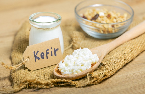 borcan cu kefir, castronel cu muesli si lingura de lemn cu branza dulce