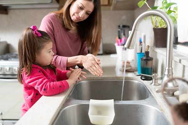 mama si fetita in bucatarie, mama incercand sa o instruiasca pe fetita sa se spele corect pe maini