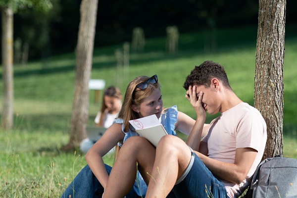 tanara care incearca sa consoleze un adolescent deprimat din cauza unui rezultat slab la invatatura 