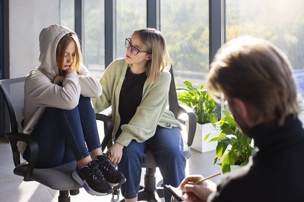 adolescenta deprimata stand pe scaun in timpul unei sedinte de terapie de grup