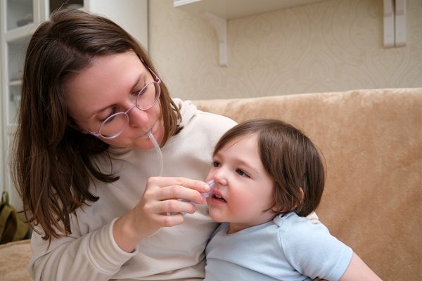 mama care aspira cu aspiratorul secretiile nazale ale baietelului ei