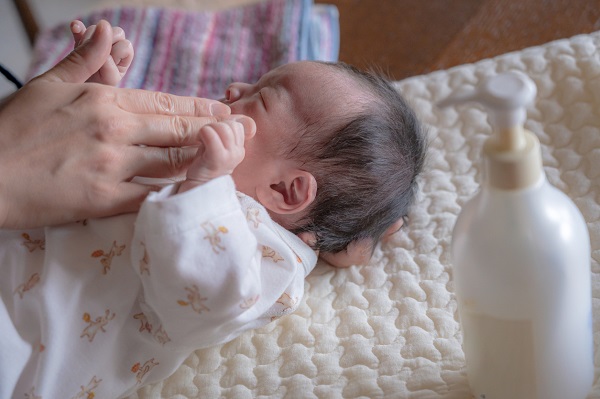 femeie care are grija de un nou-nascut si vrea sa-i aplice un produs de ingrijire a pielii