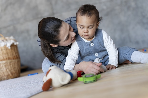 mama care se joaca pe podea cu bebelusul ei