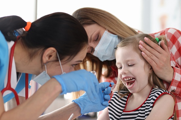 cadru medical care ia o proba de exsudat faringian de la o fetita insotita de mama ei