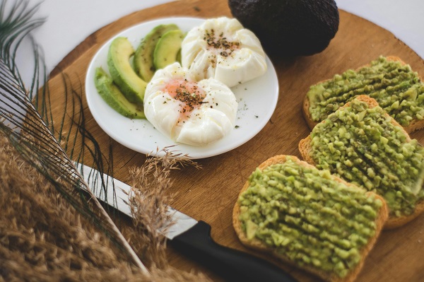 farfurie cu felii de avocado si oua plus sandvisuri cu pasta de avocado