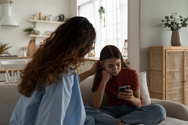 fata care se uita pe telefon mama ii aranjeaza parul