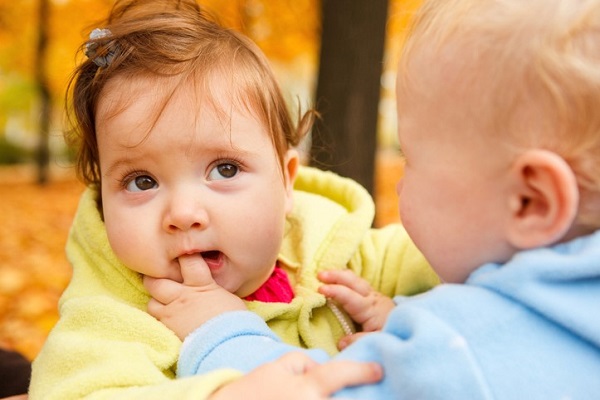 o fetita musca degetul unui alt bebelus