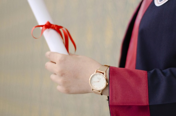 absolvent cu diploma legata cu funda rosie in mana