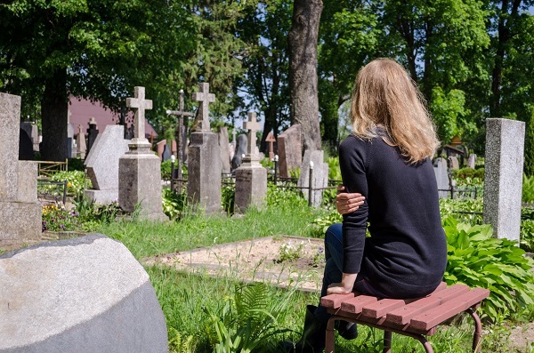 femeie plange la un mormant la cimitir