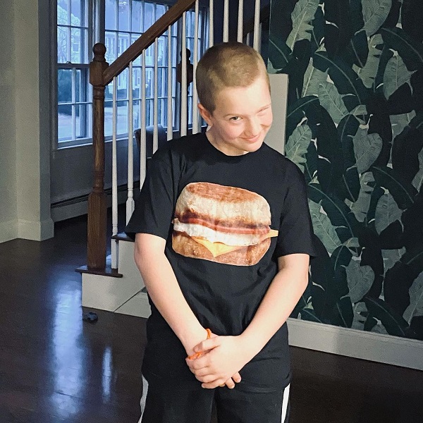 baiat cu tricou negru cu burger pe el face cu ochiul