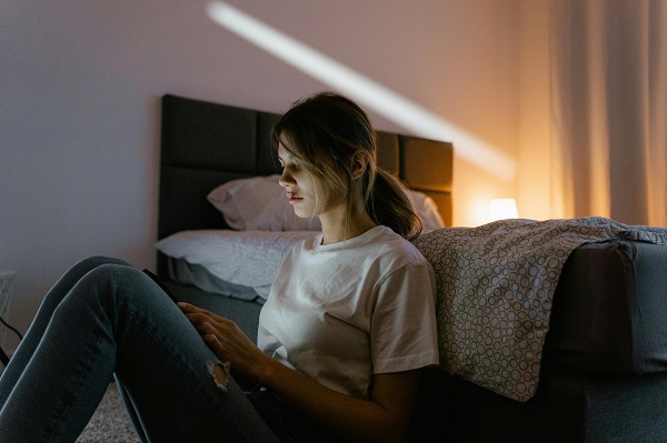 femeie agresata sta pe telefon langa un pat