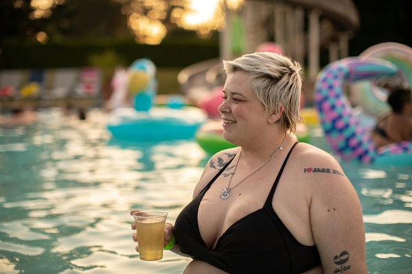 femeie supraponderala cu bautura in mana in piscina