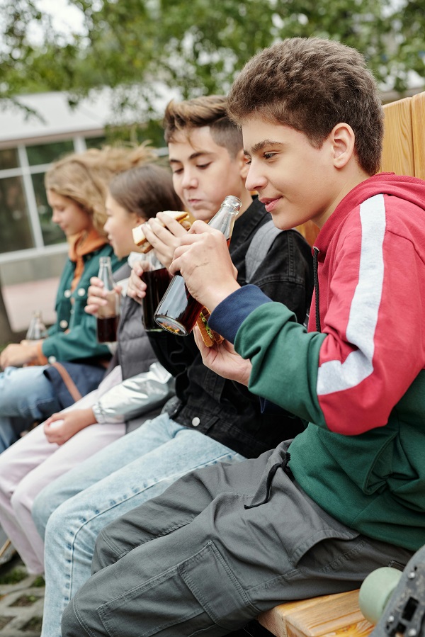 adolescenti in pauza mananca sendvis si beau suc