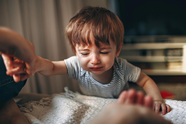 copil mic plange la masa cand este tinut de mana de un adult