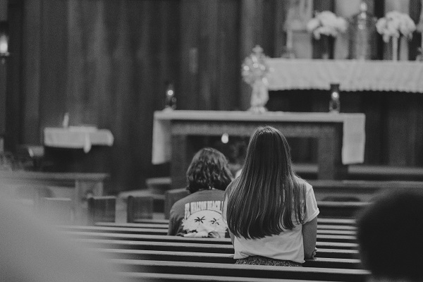 o femeie in spatele unui baiat in biserica stau la slujba