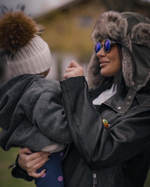 marisa paloma cu ochelari la ochi isi tine fiica cu caciula pe cap in brate