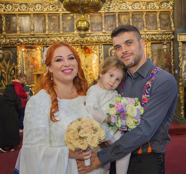 oana roman imbracata in alb alaturi de marius elisei care o tine in brate pe isabela in biserica